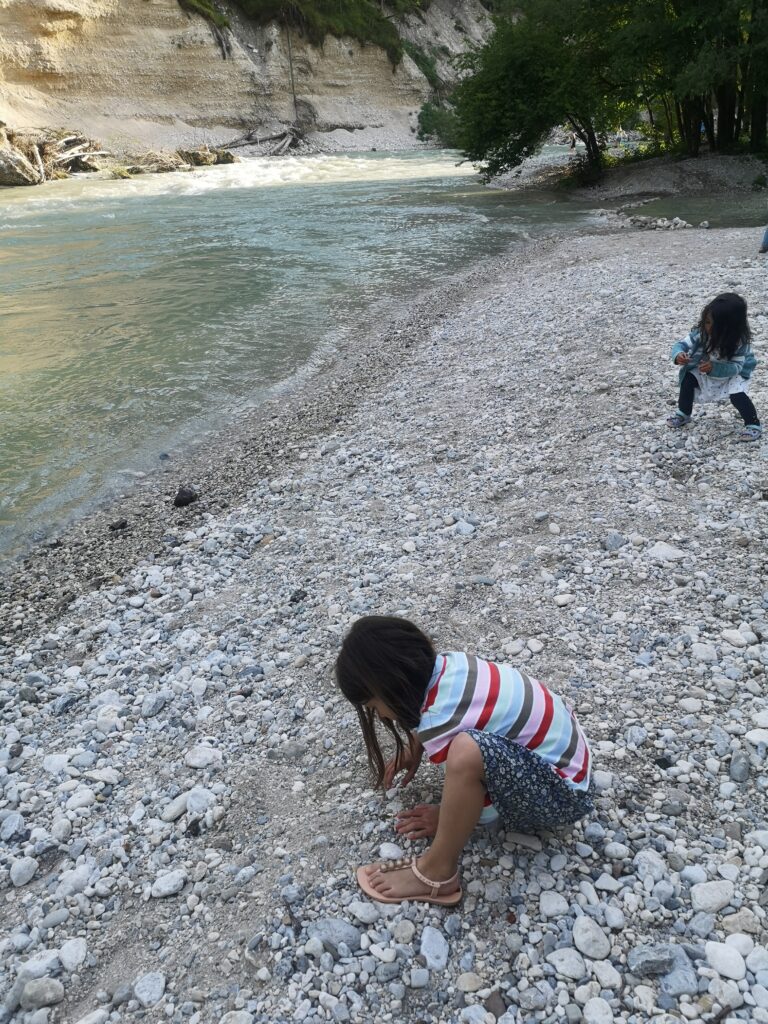 Kinder am Fluss werfen Steine ins Wasser